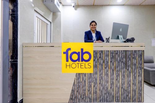 a woman standing at a desk with aida hotels sign at FabHotel Shivangan in Vrindāvan