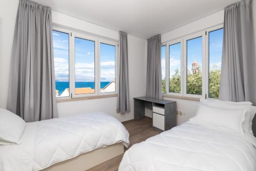 two beds in a room with large windows at APARTMENT MARCELA SUTIVAN - large two-bedroom apartment with two bathrooms - excellent location right by the town center and the beach - parking space provided - panoramic view of the sea and the town in Sutivan