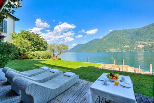 a patio with a table and chairs and a view of a lake at Maison Sur l'Eau - Lugano Villa with View Terrace in Paradiso