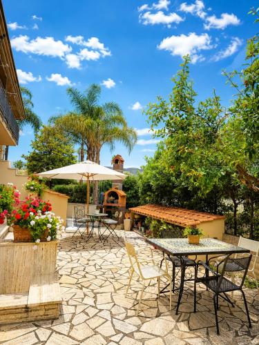 a patio with tables and chairs and an umbrella at Avola Garden Apartment near Pantanello Beach in Avola