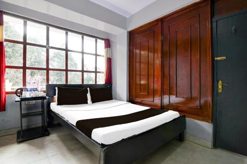 a bed in a room with a large window at Hotel O Ghoom Formerly Aps Homestay in Darjeeling