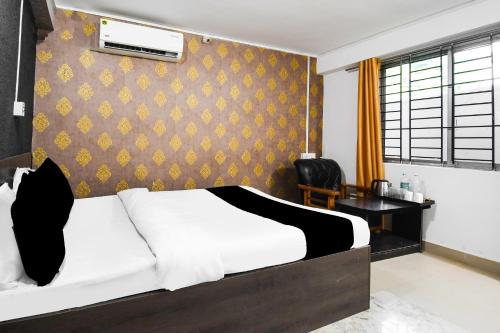 a bedroom with a white bed and a wall at Hotel O Champasari Siliguri Formerly Four Fox Suits in Siliguri