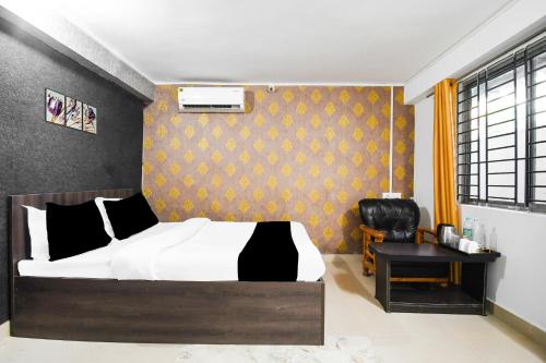 a bedroom with a bed and a chair at Hotel O Champasari Siliguri Formerly Four Fox Suits in Siliguri