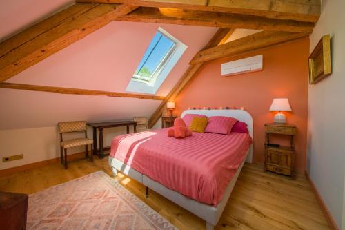 a attic bedroom with a bed and a window at La maison des jours heureux in Leysse