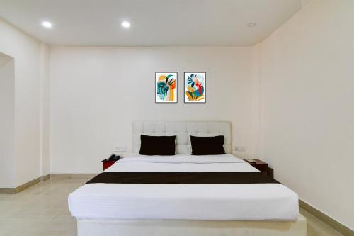 a bedroom with a large white bed with two paintings on the wall at Hotel O Kanchenjunga Stadium Formerly Bindhan's Inn in Siliguri
