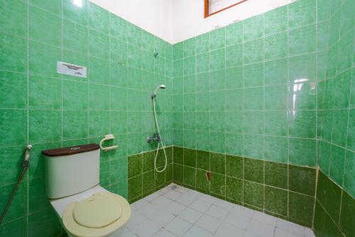 a green tiled bathroom with a toilet and a shower at Villa Tjokro 1 By ARBA in Sampal 2