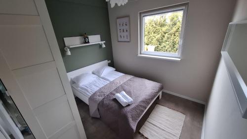 a small bedroom with a bed and a window at Repos Domki Łeba in Łeba