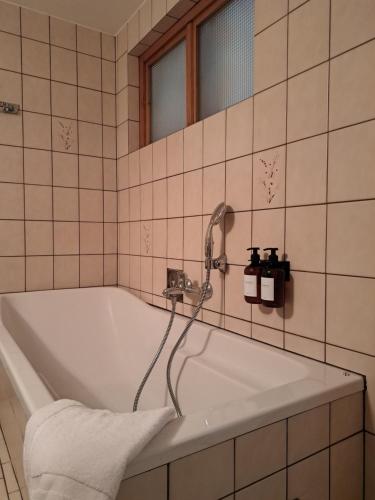 a bath tub with a shower in a tiled bathroom at Hotel Bezold in Rothenburg ob der Tauber