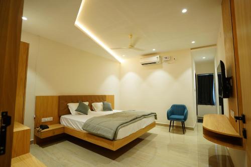 a bedroom with a bed and a blue chair at Golden Tulip Peddapally in Peddapalli