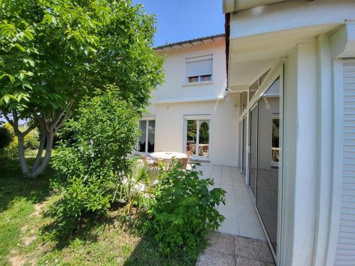 a white house with a patio and a tree at Maison venitia 14 personnes in Aussonne
