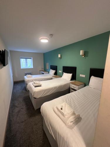 a hotel room with four beds with white sheets at The Cotteridge Inn in Birmingham
