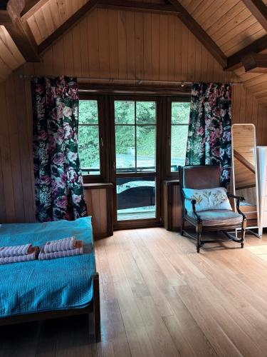 a room with a bed and a chair and windows at Hubertówka Dom in Ujanowice