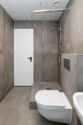 a bathroom with a toilet and a shower and a door at Air Kaunas apartment in Karmėlava