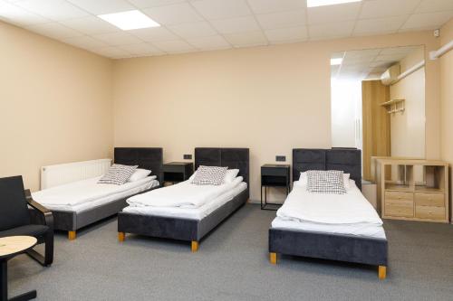 three beds in a room with tables and chairs at Air Kaunas apartment in Karmėlava