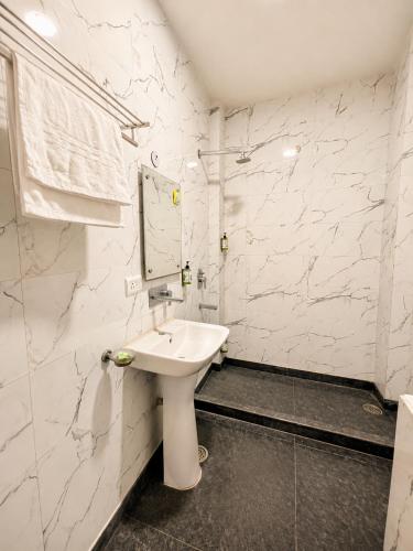 a white bathroom with a sink and a mirror at The Milford Noida in Noida