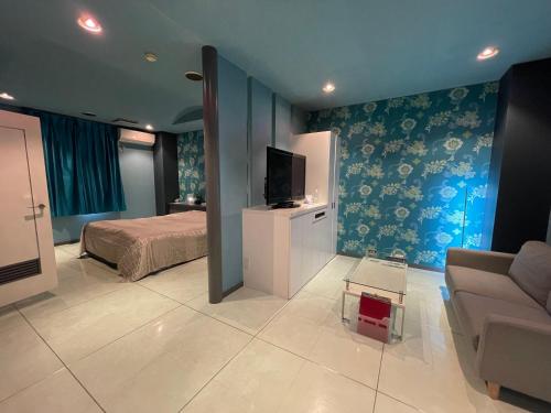 a bedroom with a bed and a couch and a tv at ホテル アクティ エクシブ in Asahi