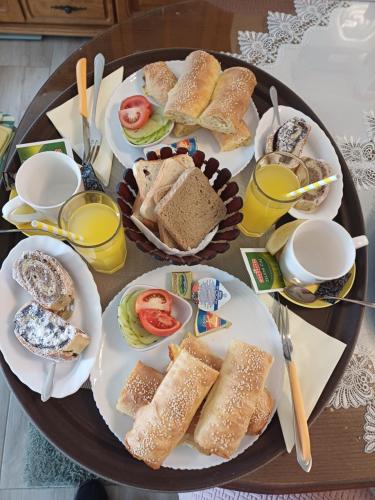 a table with plates of sandwiches and cups of orange juice at Vila Danida in Žabljak