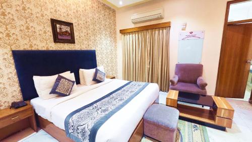 a hotel room with a bed and a chair at Buddha Heritage in Patna