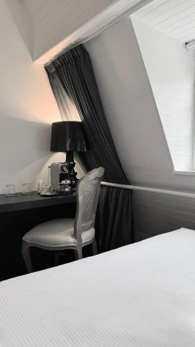 a bedroom with a bed and a desk and a lamp at Hôtel Rohan Strasbourg in Strasbourg