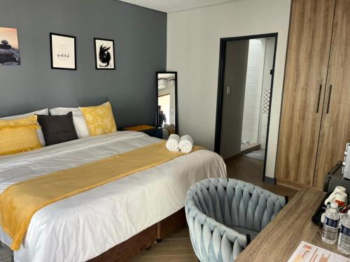a bedroom with a large bed and a chair at Black Villa Lodge in Hammanskraal