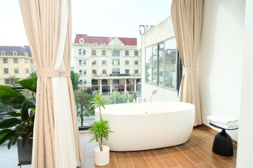 a bath tub in a bathroom with a large window at ARIA Hotel in Ninh Binh