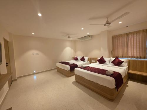a hotel room with two beds and a window at Kovil Vaasam in Tiruchirappalli