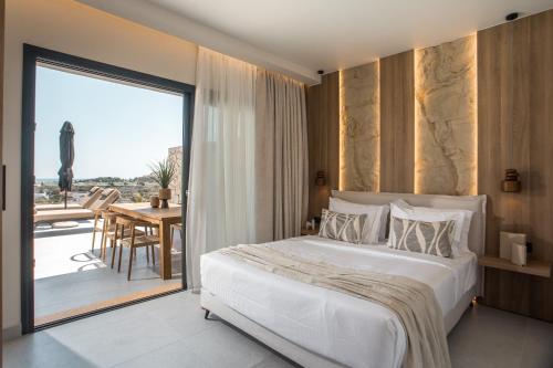 a bedroom with a bed and a balcony with a table at Celeste Luxury Villas in Lartos