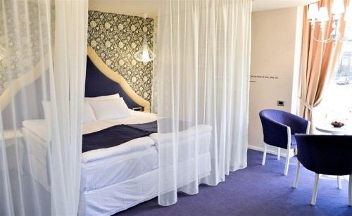 a bedroom with a bed with curtains and a table at Hotel Capitolina City Chic in Cluj-Napoca