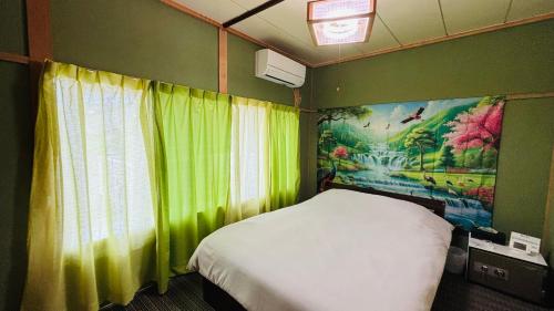 a bedroom with a white bed and a green wall at SIBARIAN White House in Kaga