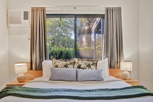 a bedroom with a bed and a large window at Pearl Escape in Broome