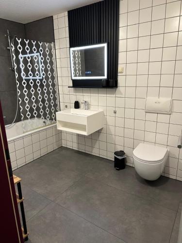 a bathroom with a toilet and a sink and a tv at Apartmenthaus Zeuthen 1 in Zeuthen