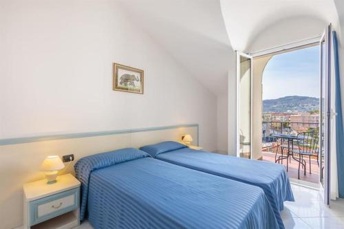 a bedroom with a blue bed and a balcony at Hotel Residence Mediterraneo in Diano Marina