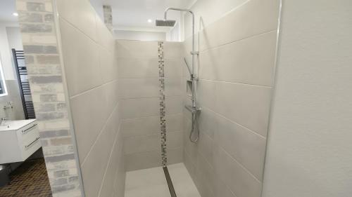 a shower in a bathroom with white tiles at Fewo Carpe Diem in Scheuerfeld