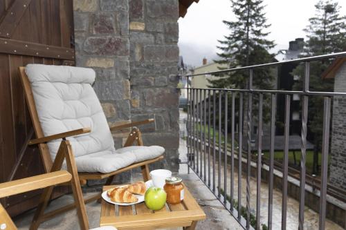 a chair and a table with a plate of food on a balcony at Acentor Alpino by BeValle in Panticosa