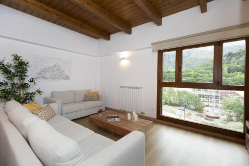 a living room with a white couch and a large window at Sueños del Garmo by BeValle in Panticosa