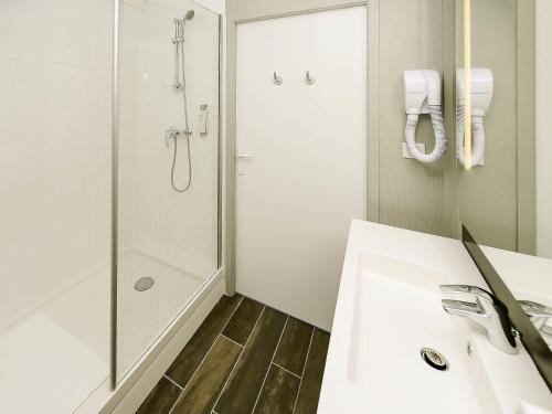 a white bathroom with a shower and a sink at ibis Lyon Est Beynost in Beynost