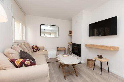 a white living room with a couch and a fireplace at Sky Biescas I by BeValle in Biescas