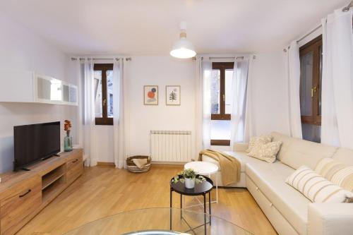 a living room with a white couch and a tv at Calma by BeValle in Panticosa