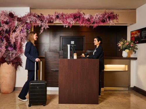 two women standing at a cash register in a lobby at Novotel Paris La Defense Esplanade in Courbevoie