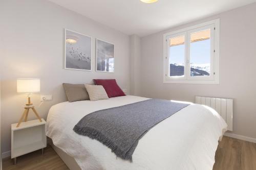 a bedroom with a white bed and two windows at La Ventana de Formigal by BeValle in Formigal