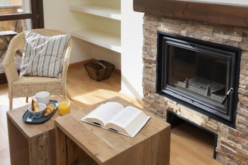 a living room with a fireplace and a table with a book at CuMbre del Sarrio by BeValle in Panticosa