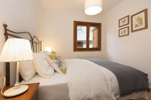 a bedroom with a bed with a lamp and a window at Rincón del Pueyo by BeValle in El Pueyo de Jaca