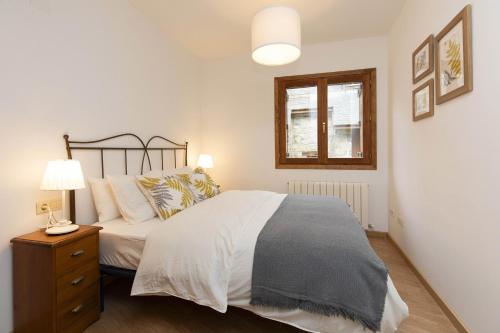 a bedroom with a bed and a nightstand and a window at Rincón del Pueyo by BeValle in El Pueyo de Jaca