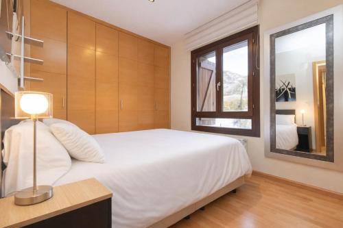 a bedroom with a white bed and a window at Altos de Argualas by BeValle in Panticosa