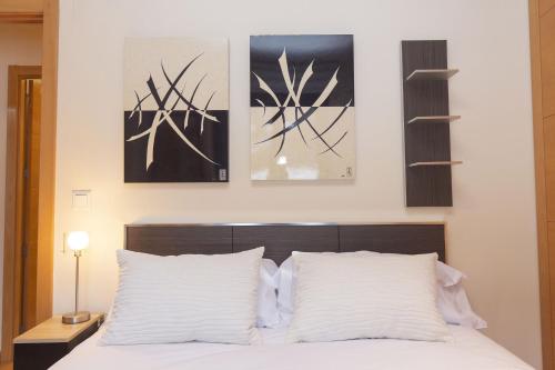 a bedroom with a white bed with three pictures on the wall at Altos de Argualas by BeValle in Panticosa