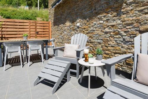 a patio with chairs and a table and a stone wall at El Rincón del Verde by BeValle in Panticosa