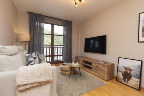 a living room with a bed and a flat screen tv at Casa Lluna by BeValle in El Pueyo de Jaca