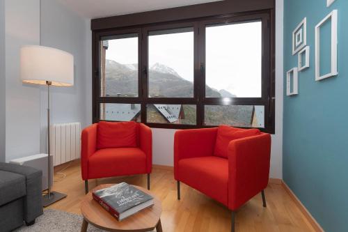 a living room with two red chairs and a window at Narnia by BeValle in Panticosa