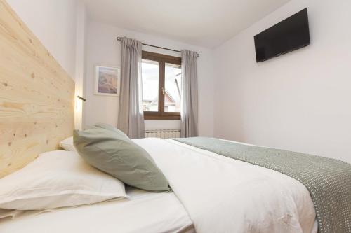 a bedroom with a bed and a television on the wall at Sueños de Telera by BeValle in El Pueyo de Jaca