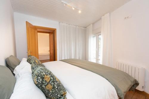 a bedroom with a white bed with pillows on it at Panorámica del Valle II by BeValle in Panticosa